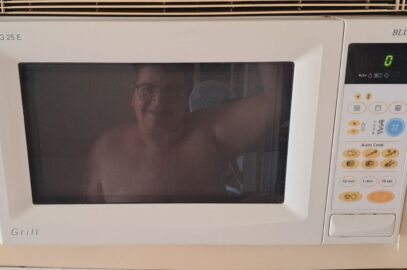 Reflejo de Maria Rosa Aleixandre Maset en la puerta de un microondas, ilustrando el paso de microondas a puchero en relaciones y emociones.